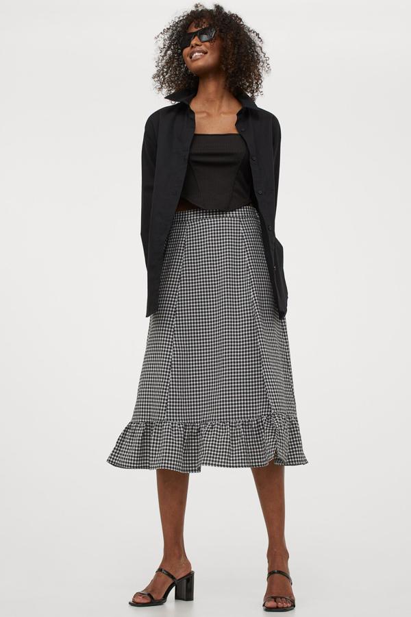 De talle alto, con elástico revestido en la espalda, volante ancho en el bajo y abertura en un lateral, esta falda midi con estampado de cuadro vichy es de H&M podemos encontrarla entre las tallas XS y XL por 19,99 euros.