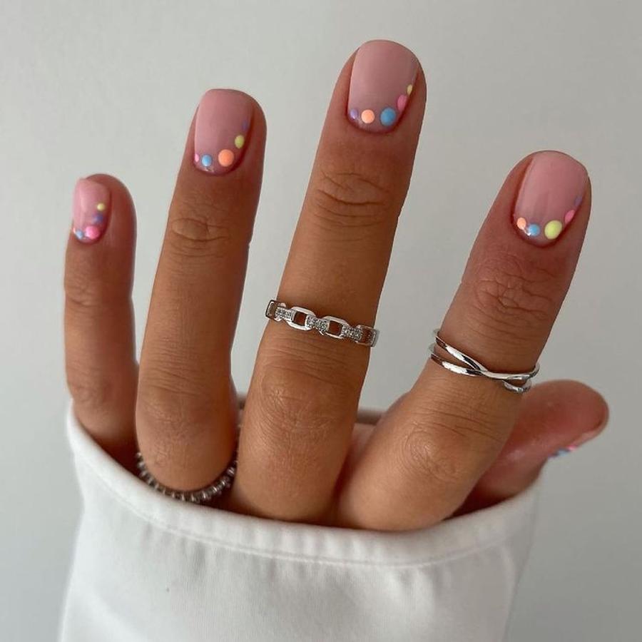 ¿Hay una manicura más ideal y fácil de hacer que esta? Opta por una base neutra y añade puntitos de colores en un lateral de la uña. ¡Monísima!