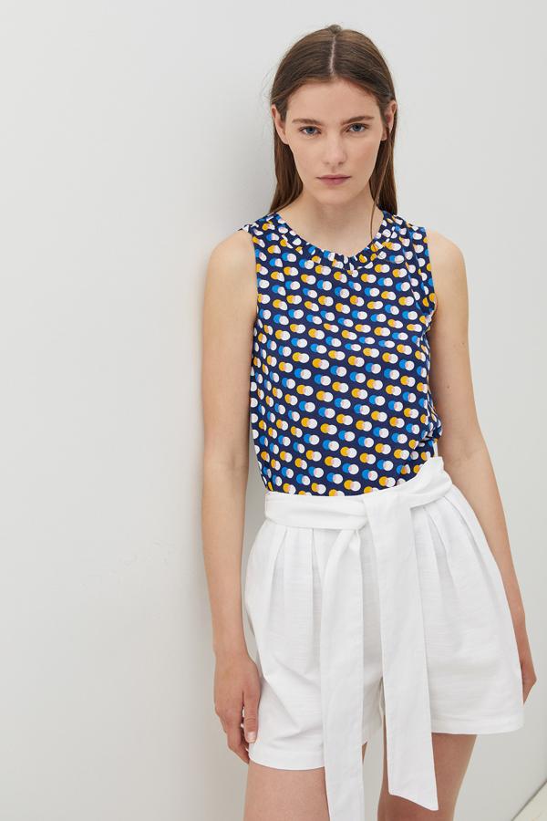 Con cuello caja, sin mangas y confeccionada al 100% en algodón, esta camiseta en azul marino con estampado de lunares azules, mostaza y blancos tiene un precio de 5,99 euros, y está disponible entre las tallas S y XL.