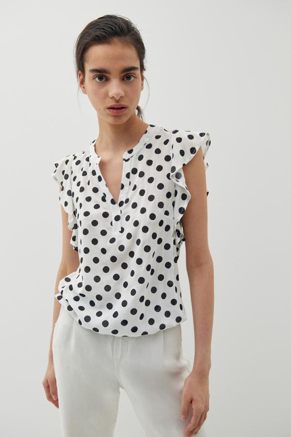 Con volantes en las mangas sisa y escote de pico, esta camisa en color blanco con lunares negros tiene un precio de 13,99 euros y está disponible en las tallas S, M y L.