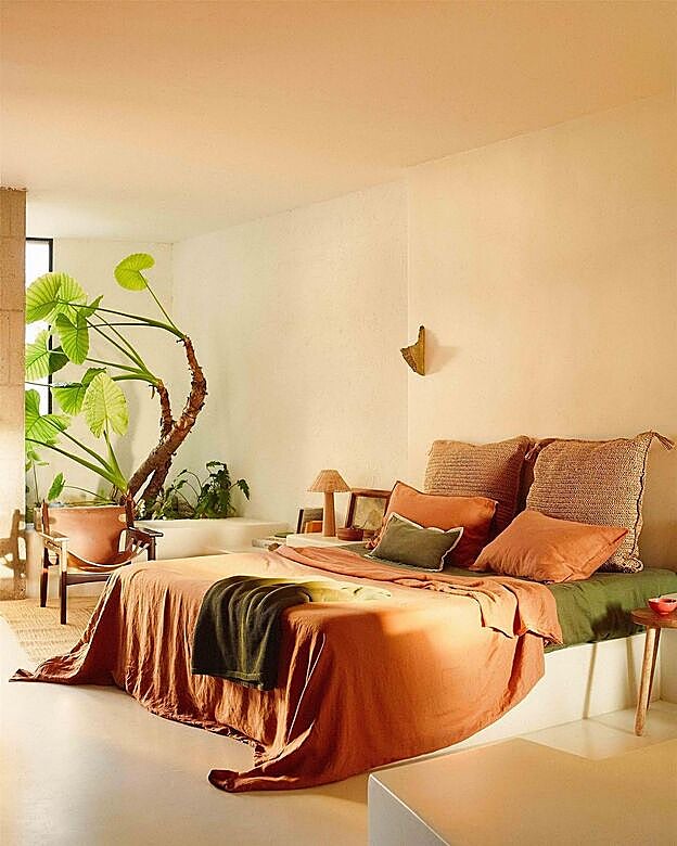 Ropa de cama con textiles en naranja y plantas.
