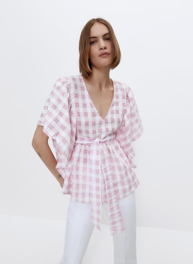 Con estampado de cuadros vichy en color rosa, esta camisa con volantes en los hombros y cinturón tiene un precio de 69 euros.