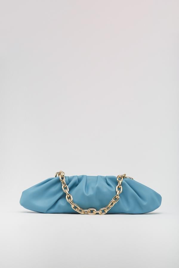 Diseño baguette fruncido en color azul pastel para este bolso de cierre con imán y cremallera en el interior que viene con cadena dorada de eslabones medios. De 19,99 euros ha pasado a 15,99 euros. 