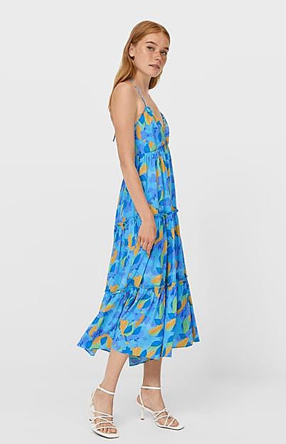 Es un vestido azul con un estampado con mezcla de verde y mostaza.