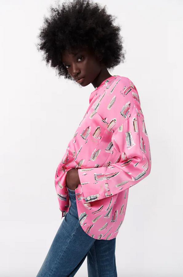 Estampado de edificios sobre fondo fucsia para esta camisa fluida con cuello redondo subido y manga larga acabada en puño. De 29,95 euros ha pasado a costar 19,99 euros. 