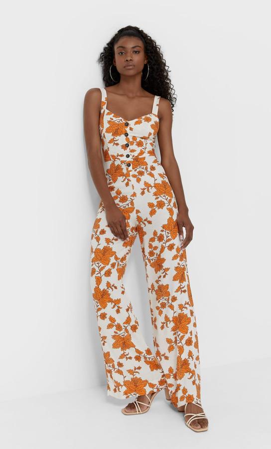 En color crudo con estampado naranja, este mono de lino con tirantes anchos y botones en la parte frontal es de Stradivarius y tiene un precio rebajado de 19,99 euros.