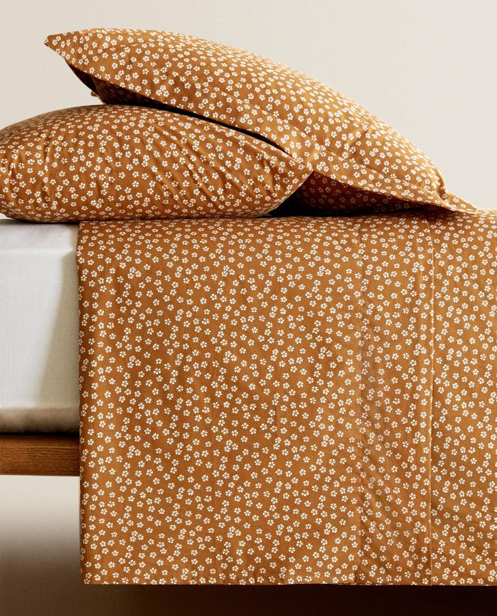 Disponible en varios tamaños, esta sábana encimera de algodón percal de 200 hilos en color mostaza y con pequeñas flores en blanco tiene un precio entre 12,99 euros y 29,99 euros.