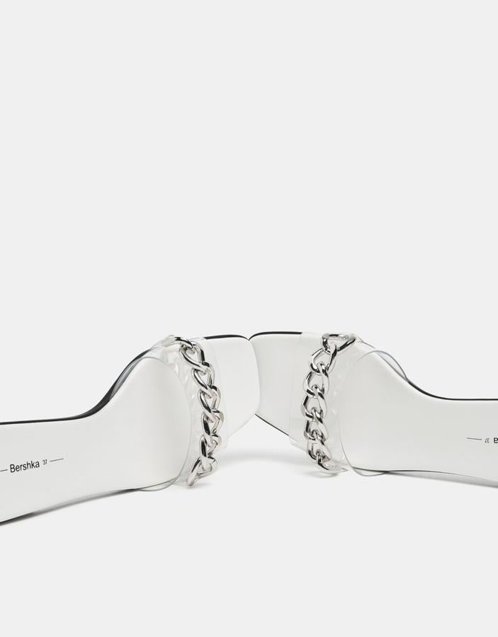 Con empeine en vinilo transparente con cadena en la pala, estas sandalias de punta cuadrada y suela blanca han pasado de 22,99 euros a 12,99 euros. Podemos encontrarlas entre los números 35 y 41. 