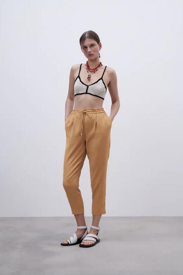 En camel medio, negro y beige, este pantalón pijamero de tiro alto de Zara con cintura elástica ajustable con cordón y pliegues delanteros viene con bolsillos laterales y bajo por encima del tobillo. Con un precio de 19,95 euros, están disponibles entre las tallas XS y XXL. 