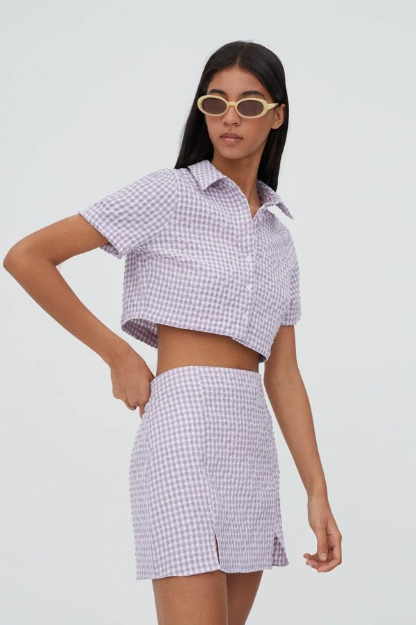 De manga corta y con estampado de cuadros vichy en color malva, esta camisa de corte cropped y cierre de botones tiene un precio de 12,99 euros (antes 17,99 euros).