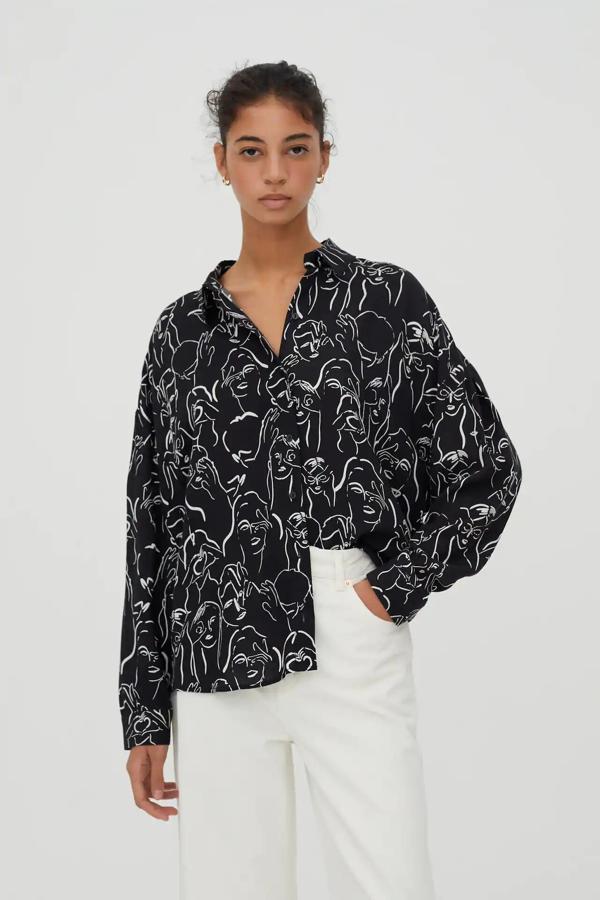 Esta camisa negra con estampado de caras en color blanco cuenta con cierre mediante botones y tiene un precio rebajado de 9,99 euros (antes 17,99 euros).