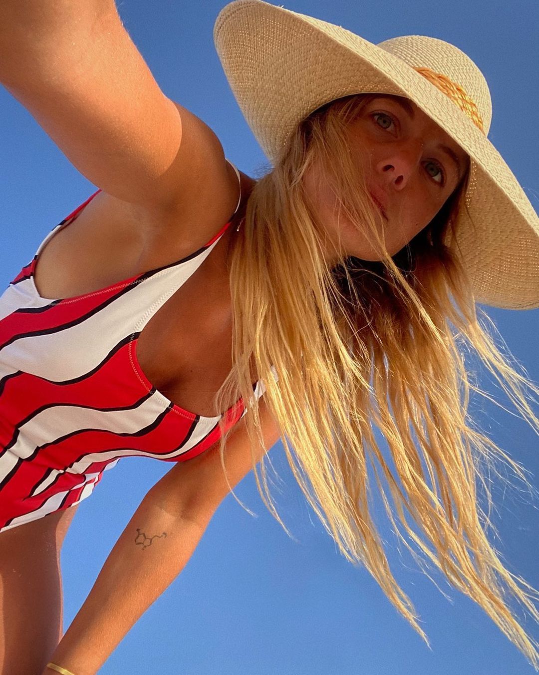 Mujer con pelo rubio y bañador de rayas en rojo y blanco.