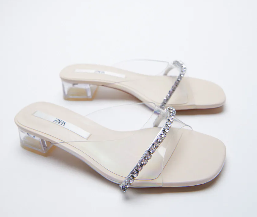 Estos mules de tacón cómodo en vinilo con detalle joya de strass están rebajados a 19.99 euros en Zara.