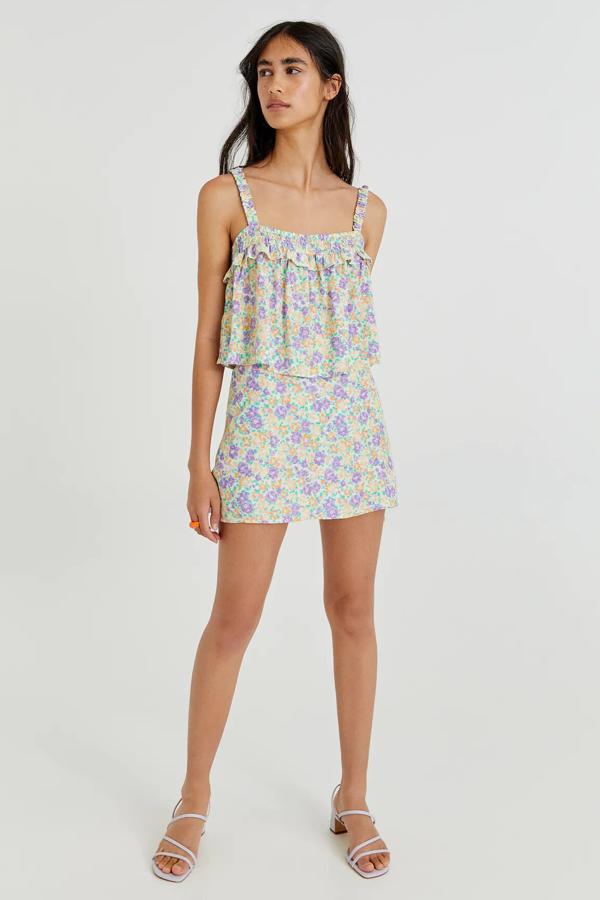 Disponible en varios tonos, este conjunto con estampado floral está formado por una falda pantalón (15,99 euros) y un top (15,99 euros) de tirantes con volantes. 