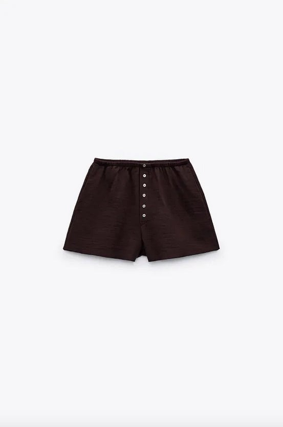 En marrón oscuro, con tiro alto y cintura elástica, estos shorts de Zara con bolsillos laterales y falsos botones en delantero combinados a contraste están confeccionados al menos con un 50% de algodón orgánico. De 19,95 euros han pasado a costar 9,99 euros. 