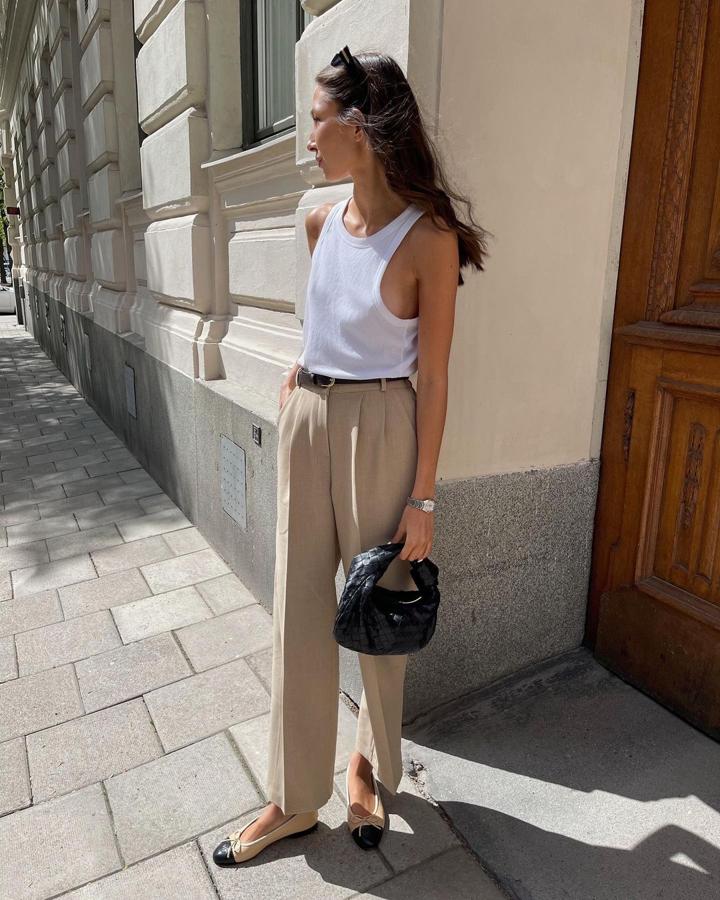 Básicos y más básicos. Camisa de tirantes blanca más pantalón de pinzas beige, como para negarse. Termina el outfit con bailarinas o sandalias, un mini bolso y un cinturón fino, que estilice más el cuerpo.