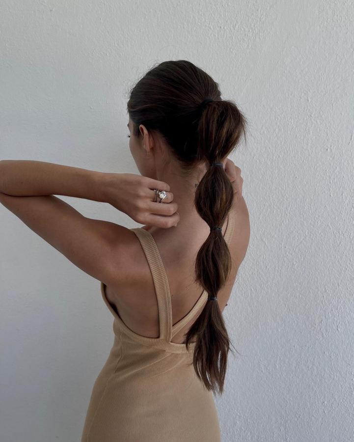 La coleta burbuja es muy sencilla de hacer. Solo debes recogerte el pelo en una cola (alta, media o baja) e ir atando gomillas a lo largo. Si quieres que quede más sofisticada, puedes abrir cada 'burbuja', para tener mayor volumen, y enredar un mechón de pelo alrededor de cada gomilla para taparlas.