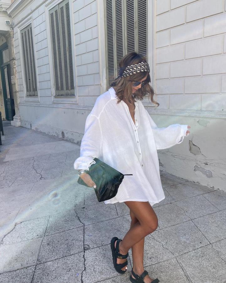 Una camisa oversize, ya está. Eso es lo único que querrás llevar. Esta influencer la usa a modo de vestido, aunque si no te sientes cómoda llevándola sola, pon unos pantalones cortos debajo. Estiliza con sandalias 'ugly shoes' con tiras de velcro, un bolso de mano grande y un pañuelo a modo de diadema.