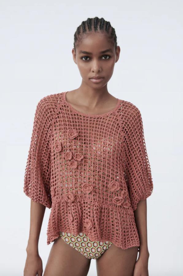 De cuello redondo y mangas hasta el codo este top de punto crochet en color chicle viene con detalle de estructura en forma de flor y bajo acabado en volante. Con un precio de 39,95 euros, podemo encontrarlo en las tallas S, M y L.