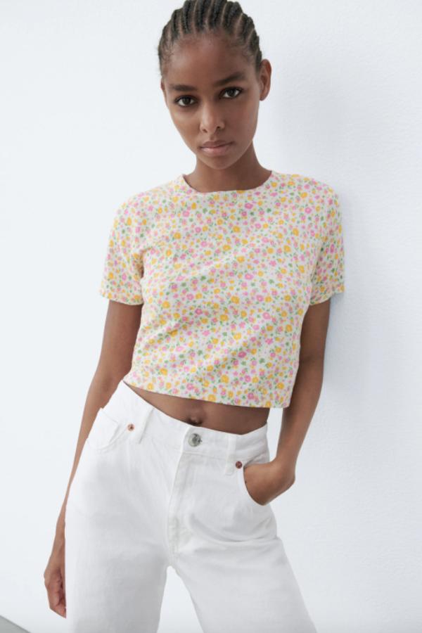 Perfecto para poner la nota de color a tus estilismos con faldas o pantalones blancos, este top de punto con cuello redondo y manga corta con estampado de flores en rosa y amarillo tiene un precio de 17,95 euros y está disponible entre las tallas XS y L.