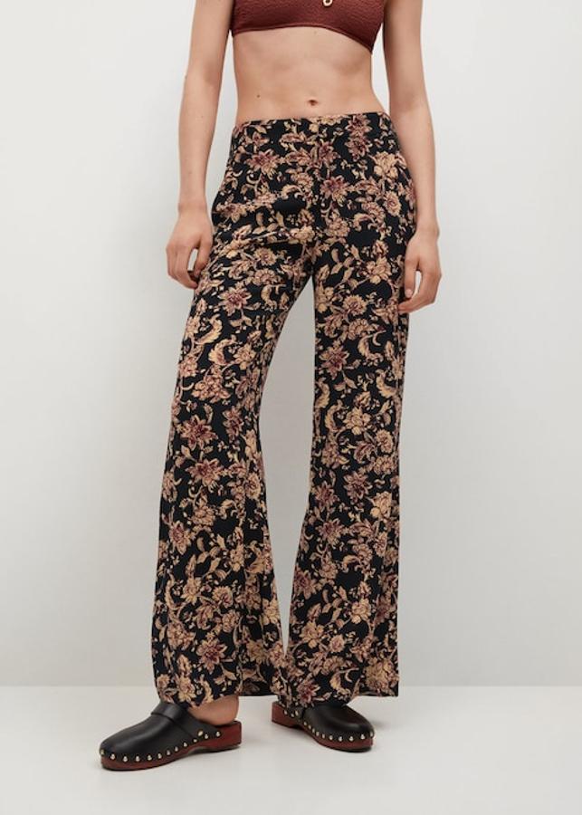 Fondo negro con estampado de flores en vainilla y granate para este pantalón de Mango de tejido fluido y diseño recto con tiro medio y cintura elástica. Tiene un precio de 25,99 euros y podemos encontrarlo entre las tallas 32 y 46.