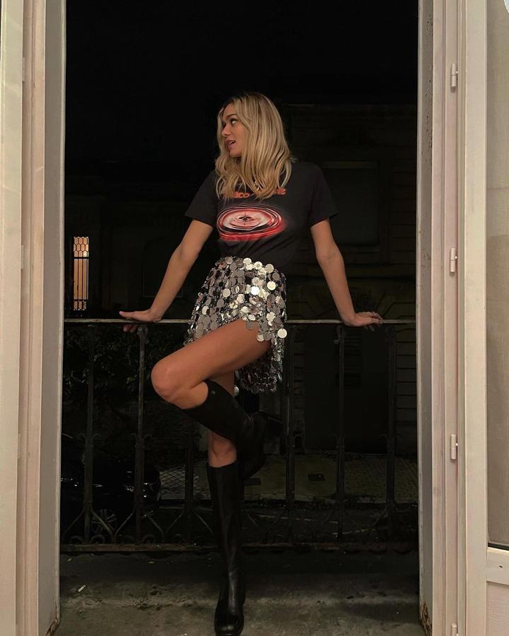 Un estilismo basado en los contrastes. Prendas informales como la camiseta gráfica junto a falda de maxi lentejuelas plateadas y unas botas altas de tacón grueso.