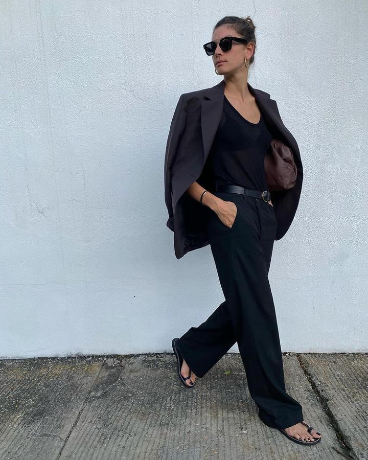 Menos es más y un estilismo todo de negro, es un ganador. Pantalones de traje, blazer a conjunto, camiseta de tirantes y sandalias. Un maxi 'clutch' marrón marca la diferencia.