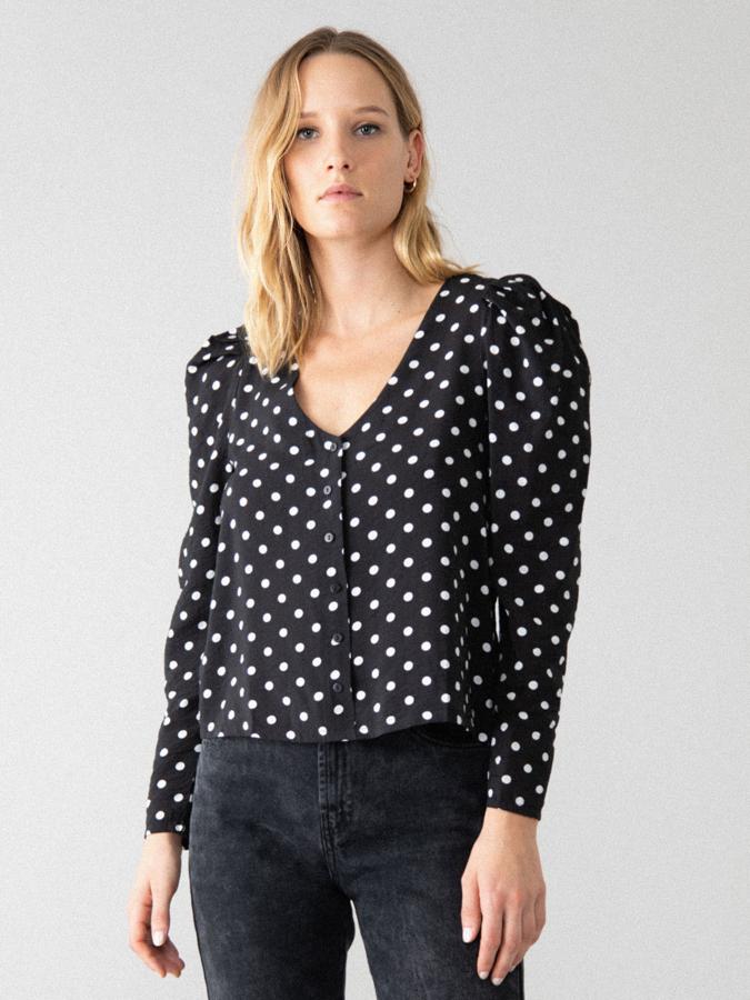 Esta camisa negra con lunares blancos cuenta con cuello pico y hombreras. De manga larga abullonada, tiene un precio rebajado de 3,99 euros (antes 12,99 euros).