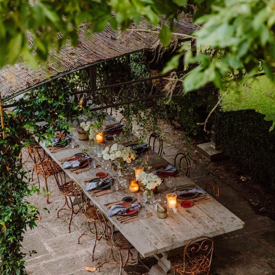 Comedor exterior con mesa alargada de madera y sillas en metal. 