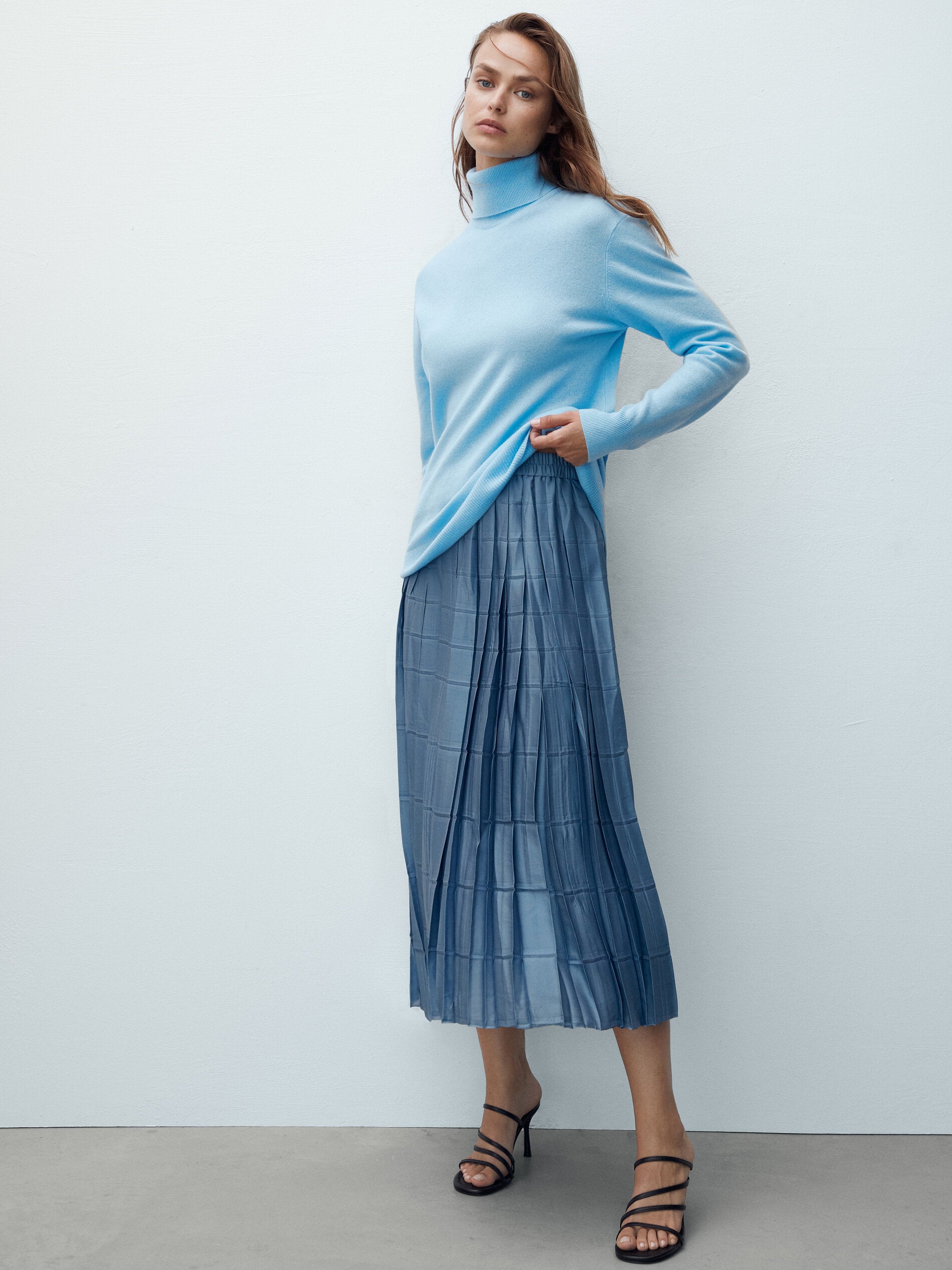 Los opuestos siguen atrayéndose. Así lo demuestra esta llamativa y efectiva combinación de tejidos: la lana y la seda. Un contundente jersey de cuello vuelto de suave cachemir se convierte en la pareja ideal de una falda midi plisada de seda. Especialmente si se juega a engamar cromáticamente ambas prendas.