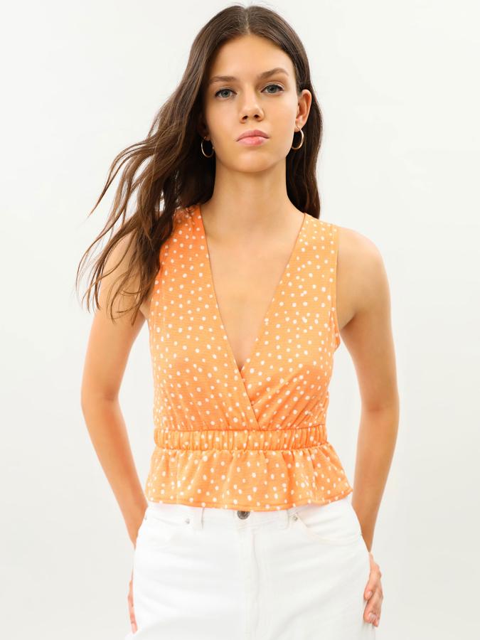 En color naranja con topos blancos, este top corto con escote cruzado y volante en el bajo tiene un precio de 5,99 euros.