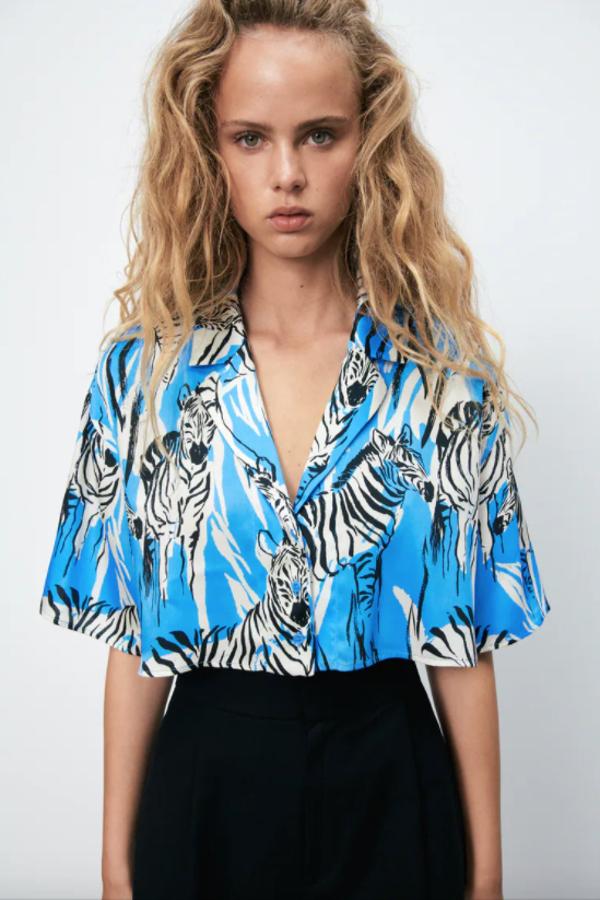 Estampado de cebras (que no de cebra) sobre fondo azul para esta camisa cropped con cuello y solapa, además de mangas cortas. Tiene un precio de 19,95 euros y podemos encontrarla entre las tallas XS y XL. 