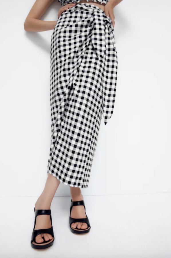 Con estampado de cuadro vichy en blanco y negro, esta falda confeccionada con tejido en mezcla de lino de Zara es de tiro alto y viene con nudo lateral y cierre de botón interior. Cuesta 25,95 euros y podemos comprarla entre las tallas XS y L. 