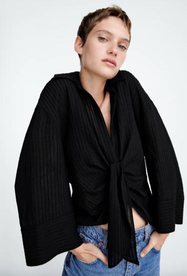 Con cuello de solapa, escote de pico y mangas largas, este top drapeado con lazada frontal y detalle de pliegues en el mismo tejido viene con bajo asimétrico. De color negro, cuesta 29,95 euros y está disponible entre las tallas XS y XXL. 