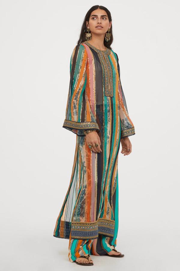 De diseño largo en gasa ligeramente arrugada con suave caída, este caftán adornado con lentejuelas y ribetes bordados en el escote, los puños y el bajo es de diseño recto con abertura en la parte superior y mangas amplias acampanadas. Tiene aberturas laterales pronunciadas y ribete de pompones en el bajo y los puños y cuesta 199 euros. 