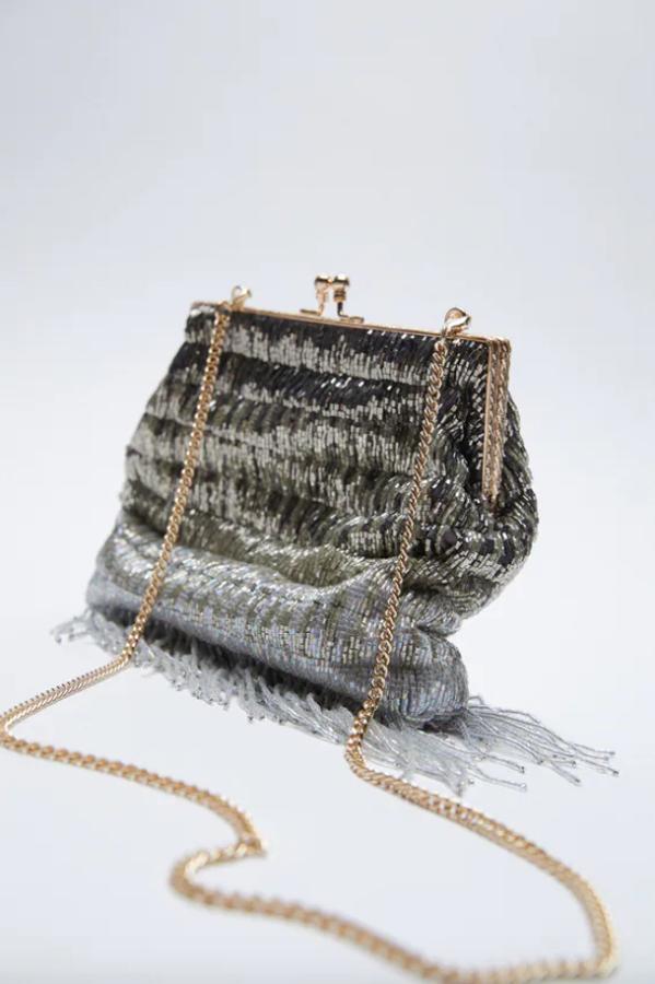 En degradación de colores que van del negro al plateado, este bolso de Zara en formato bandolera con cuerpo de abalorios y asa de hombro extraíble con cadena fina dorada tiene un precio de 39,95 euros. 