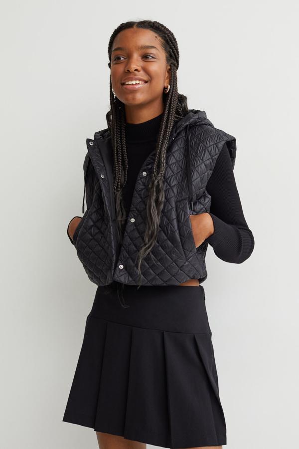 En nailon guateado con ligero acolchado y capucha con cordón de ajuste, este chaleco de diseño boxy de H&M viene con diseño de hombros ligeramente caídos, cierre de botones de presión a tono y bolsillos delanteros insertados. Con un precio de 24,99 euros, está disponible entre las tallas XXS y XL. 