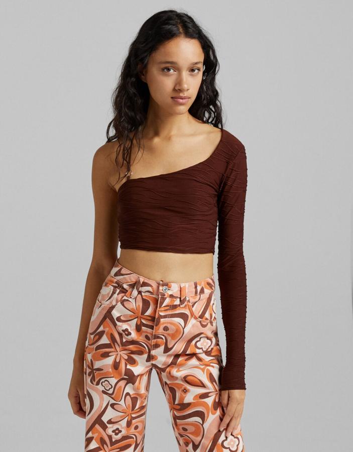 Diseño asimétrico para este top en jacquard con tejido ligeramente arrugado espalda semi descubierta y tirante fino en el lado sin manga. Cuesta 17,99 euros y está disponible entre las tallas XS y L. 