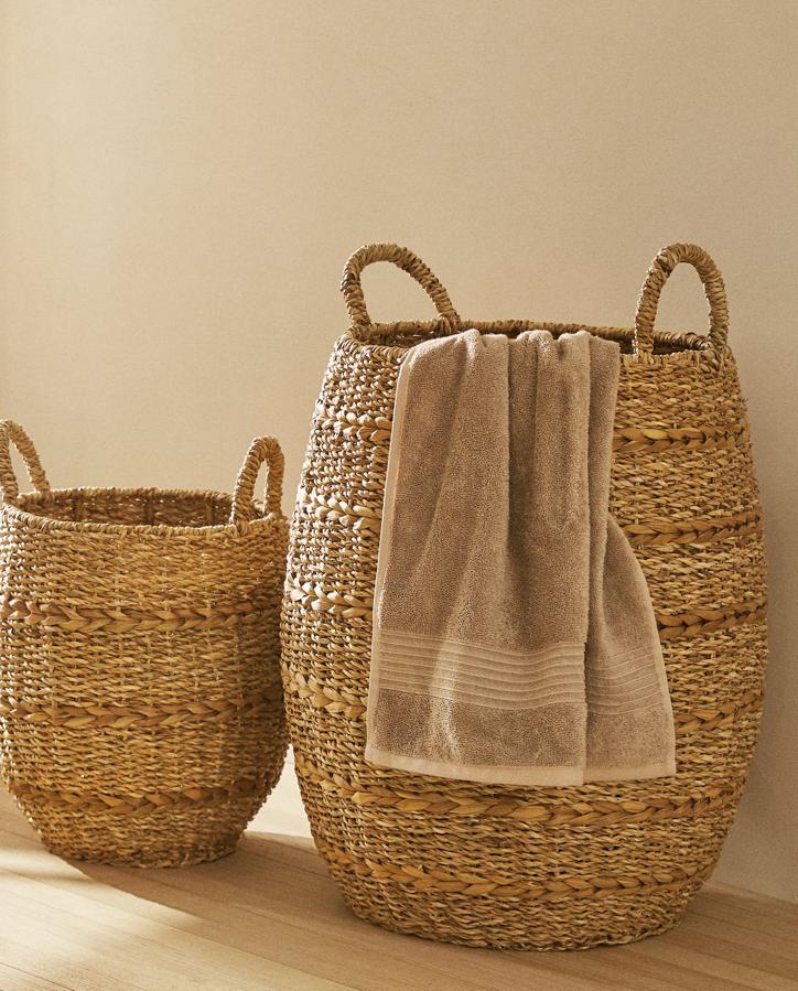 Este cesto para la ropa sucia confeccionada en seagrass con una altura de 35 centímetros y asas tiene un precio de 29,99 euros.