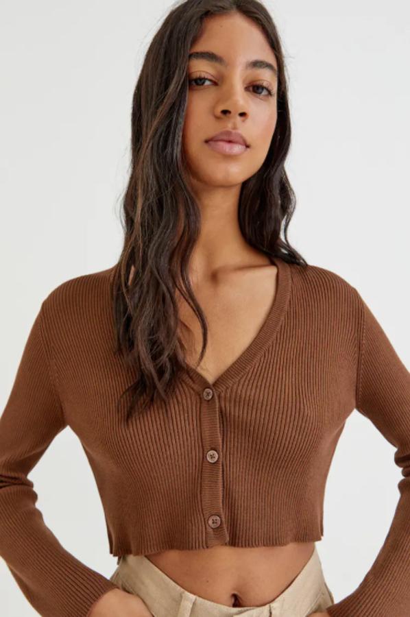Con escote de pico, cierre frontal de botones a tono y mangas largas, este cárdigan cropped de Pull &Bear en canalé está disponible en marrón y crudo, cuesta 17,99 euros y podemos encontrarlo entre las tallas XS y L.