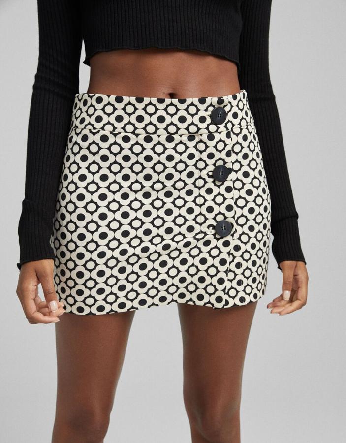 Disponible en negro o con estampados en blanco y negro o en naranja y negro, esta falda de diseño retro con falso cierre de botones a contraste en el frontal es de Bershka y podemos encontrarlas entre las tallas XS y XL por 17,99 euros. 