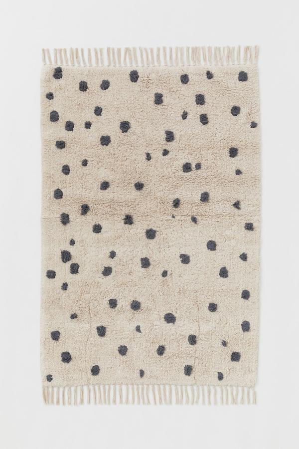 Confeccionada en 100% algodón, esta alfombra de pelo corto de color beige con lunares en gris cuenta con flecos en los extremos y protección antideslizante. Mide 90x130 centímetros y tiene un precio de 49,99 euros.