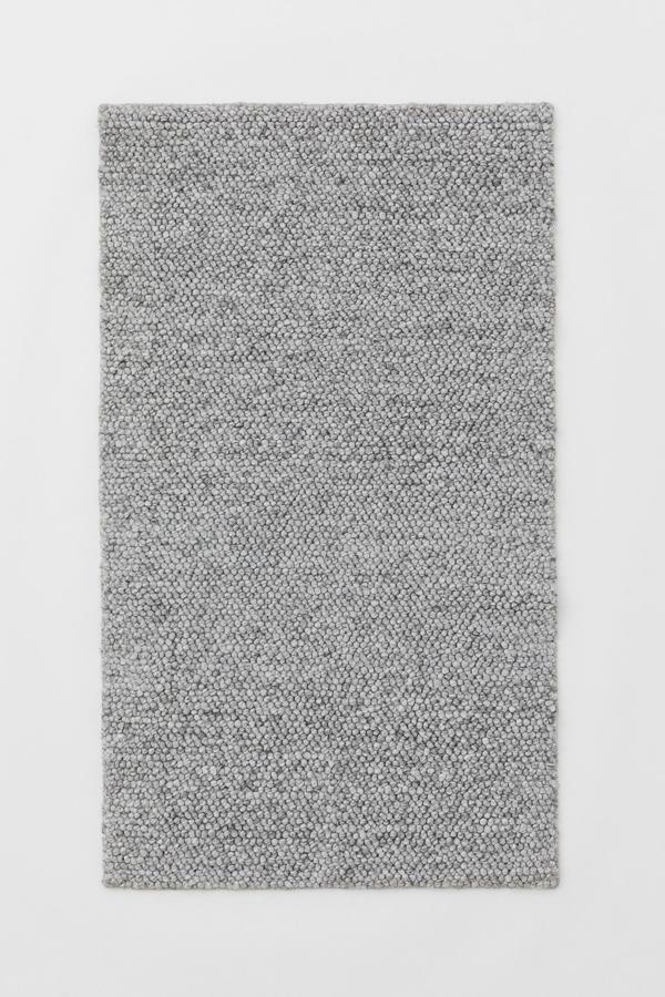 En color gris jaspeado y con una medida de 80x140 centímetros, esta alfombra en tejido con textura de mezcla de lana, algodón reciclado y poliéster de botellas PET recicladas tiene un precio de 59,99 euros.