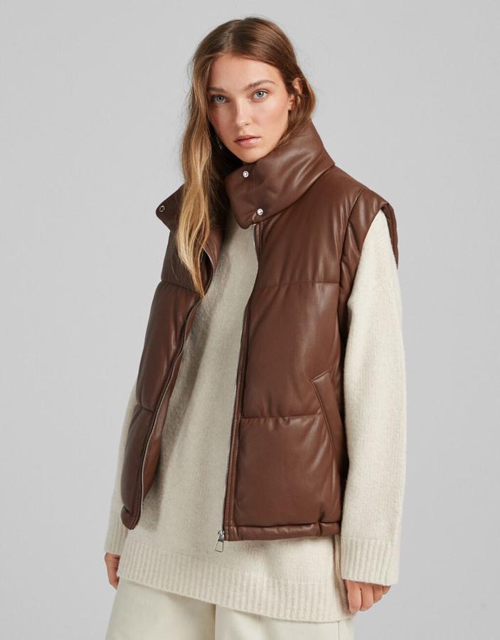 Disponible en marrón o en negro, este chaleco acolchado de Bershka en efecto piel es de diseño medio, con cierre frontal de cremallera y cuello subido con cierre de snaps. Con bolsillos laterales al bies, tiene un precio de 35,99 euros. 