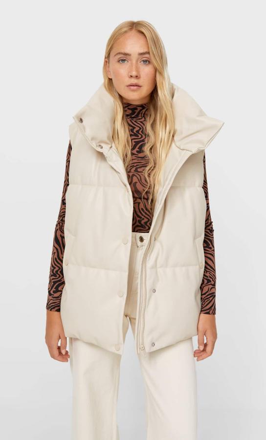 Este chaleco acolchado viene en efecto piel en color crudo y es de Stradivarius. Con cuello subido y manga sisa, viene con bolsillos de vivo con forro polar interior y cierre frontal de cremallera oculta por tapeta con botones a presión. Tiene un precio de 35,99 euros. 