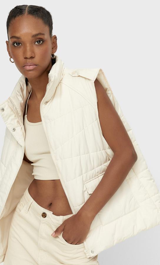 Con cuello subido y manga sisa, este chaleco con un original acolchado de Stradivarius en color vainilla tiene cierre frontal de cremallera a tono oculto por tapeta y bolsillos laterales con solapa y cuesta 25,99 euros.