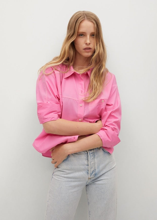 De diseño recto y con costuras a contraste en color blanco, esta camisa rosa de Mango con cuello camisero, mangas largas con puños abotonados y bolsillo de plastrón con botón en la pechera cuesta 25,99 euros y está disponible entre las tallas XS y XL. 
