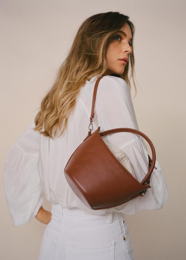 Los bolsos de rafia han dado paso a propuestas de entretiempo que se adaptan mejor a los días de lluvia. Este diseño es el perfecto bolso todoterreno para los días de otoño. Bolso color cuero de Mango (19,99 euros). 