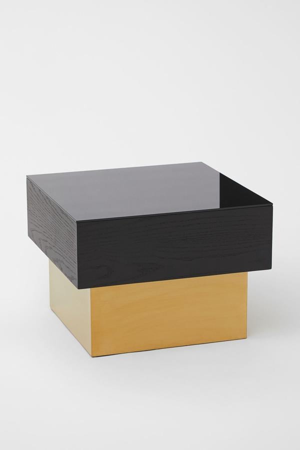 Esta mesa auxiliar en MDF con tablero de cristal y parte inferior en metal pintado tiene unas medidas de 35,5 x 49 x 49 centímetros. En negro y dorado, tiene un precio de 179 euros.