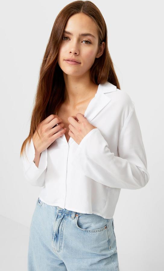 En color blanco y con cuello de pico con solapa, esta camisa corta con manga larga acampanada es de Stradivarius y tiene un precio de 15,99 euros.